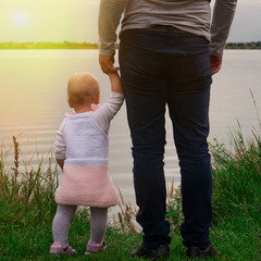 Dad teaches daughter to walk in nature. Father and daughter. First steps.