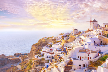 Fototapeta premium Beautiful view of picturesque village of Oia with traditional white architecture and windmills in Santorini island in Aegean sea at sunset, Greece. Scenic travel background.