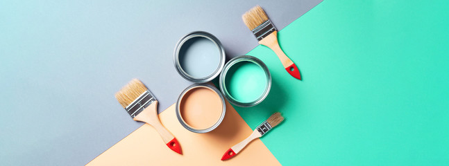 Metal paint cans and paint brushes on multicolor background. Top view. Copy space. Trendy green...