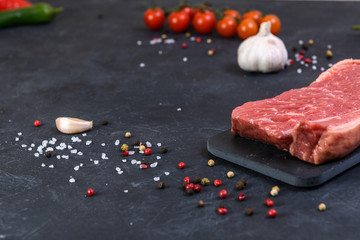 Raw fresh marbled meat and seasonings on dark background