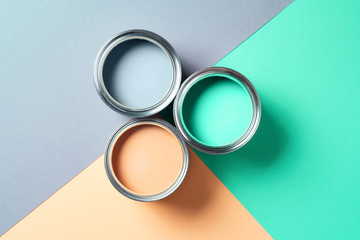 Open cans of paint on bright multicolored background. Top view. Copy space. Trendy green color...
