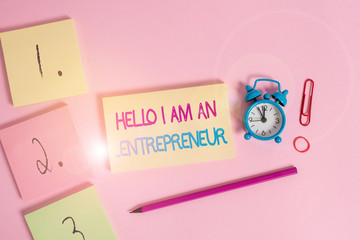 Writing note showing Hello I Am An Entrepreneur. Business concept for demonstrating who sets up a business or startups Blank notepads marker rubber band alarm clock clip colored background