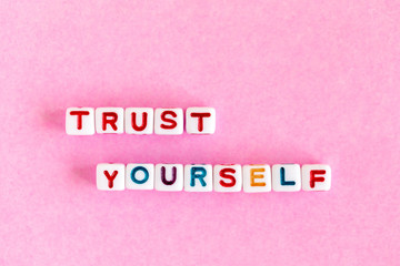Phrase "Trust yourself" made out of colorful beads, overhead view.