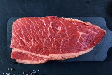 Raw fresh marbled meat and seasonings on dark background close up