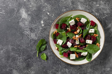 Vegetarian beetroot carpaccio salads with spinach, basil, olive oil, goat cheese, walnuts, texture background. Top view, space. Healthy eating.