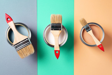 Metal paint cans and paint brushes on multicolor background. Top view. Copy space. Trendy green...