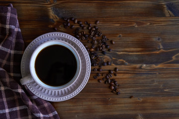 Cup of strong black coffee with coffee beans on wooden background