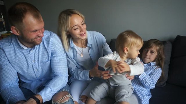 Happy family with two daughters having fun at home for the weekend. Parents and children are wearing blue jeans