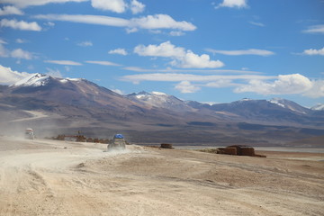  Off road in the Bolivia highlands. 4x4 vehicles cruising the dusty lanes. In the background mountains and cloudy sky