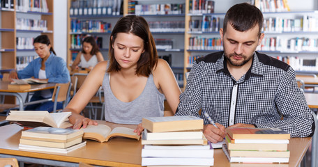 female and male students working in university library
