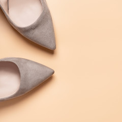 Grey suede women high heel shoes on a beige background, top view, copy space, minimal, flat lay. 