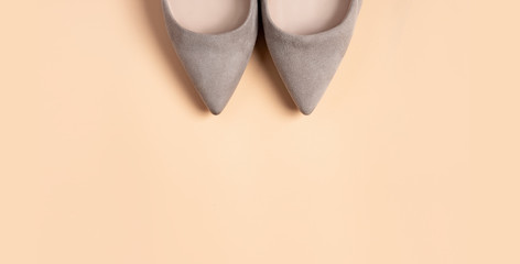 Grey suede women high heel shoes on a beige background, top view, copy space, minimal, flat lay. 