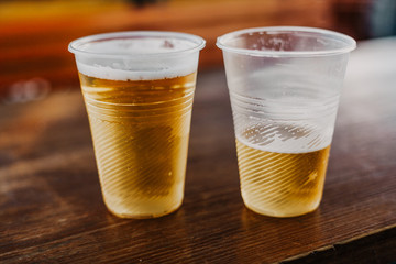 Two plastic glasses with beer stand side by side
