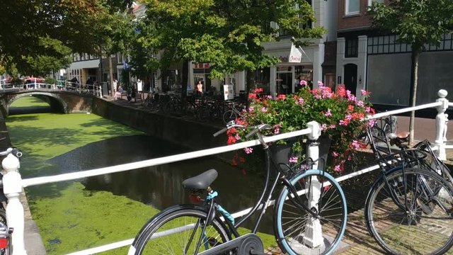 Delft, Holland, August 2019. The charming and charming canals, crossed by small bridges adorned with planters. Bikes parked. Tilt movement 30fps