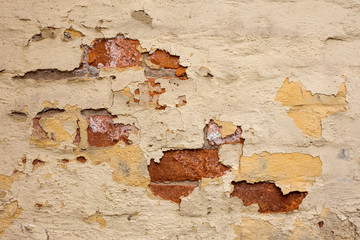 A fragment of a worn cracked decrepit once painted brick wall