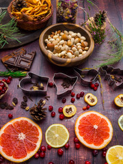 Ingredients for christmas baking spices, cookie cutters, green branch, dried apples, nuts, chocolate, fresh fruits