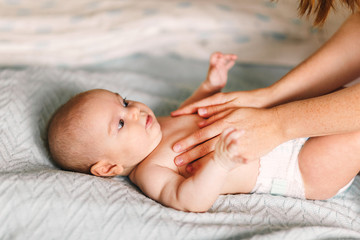 Mom hugs with her newborn baby in bed. Four month old baby. Baby care, tenderness, motherhood