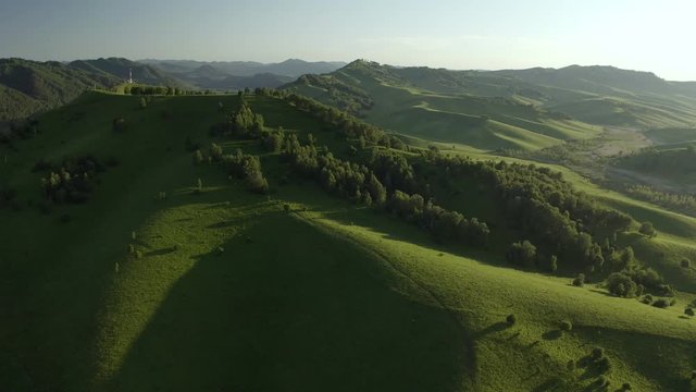 Aerial Drone Footage View: Flying over spring mountains, hills and meadows with pine forests in sun soft light. Europe. Beautiful landscape