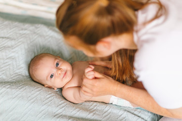 Mom hugs with her newborn baby in bed. Four month old baby. Baby care, tenderness, motherhood