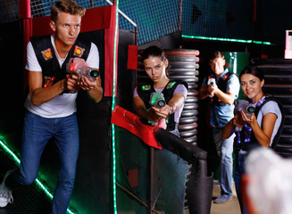 Obraz na płótnie Canvas Portrait of friends standing with laser guns during laser tag game in dark room
