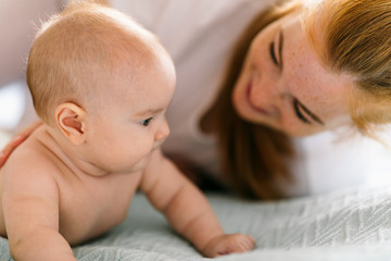 Mom hugs with her newborn baby in bed. Four month old baby. Baby care, tenderness, motherhood