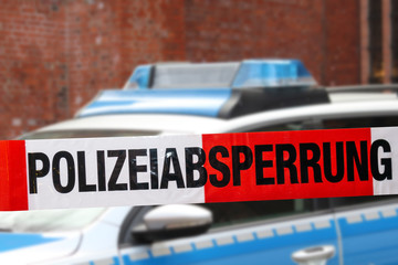 Polizeiabsperrung mit Polizeiwagen im Hintergrund