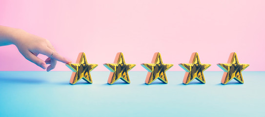 Customer review concepts with female finger and  five gold star on pastel color background