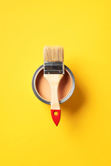 Brush and open paint can with on trendy yellow background. Top view, copy space. Appartment...