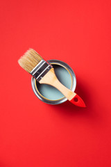 Brush and open paint can on trendy red background. Top view, copy space. Appartment renovation, repair, building and home design concept.