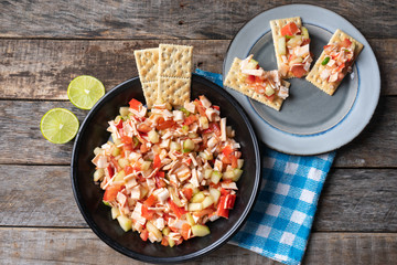 Surimi crab ceviche with cucumber and tomato on wooden background