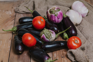 Eggplant of different varieties and tomatoes are on boards.