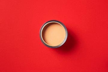 Open paint can on trendy red background. Top view, copy space. Appartment renovation, repair, building and home design concept.