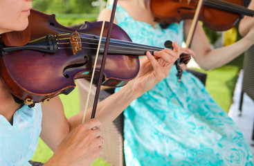 young girls play the violin at a wedding