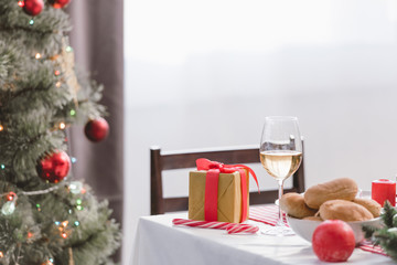 selective focus of wine glass, pies and christmas gift on table