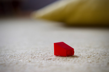 Red plastic childs building brick on a carpeted floor