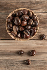 raw chestnuts in basket on a wooden table