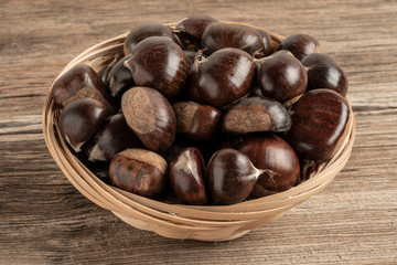 raw chestnuts in basket on a wooden table