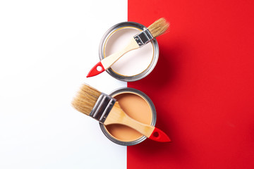 Wooden paint brushes, open paint cans on trendy red and white background. Top view, copy space....