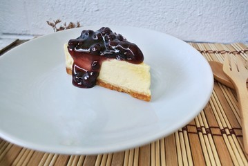 Blueberry cheesecake in a white plate on a wooden table.