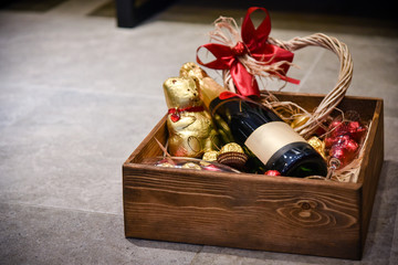 Bottle of champagne with candies and ornaments gift placed in wooden box