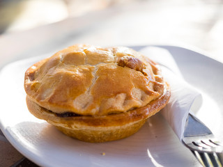 Forest Row, Sussex, UK. Meat pie on plain white plate with cutlery.
