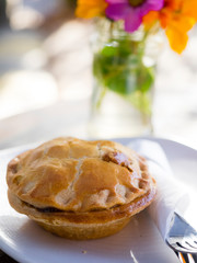 Forest Row, Sussex, UK. Meat pie on plain white plate with cutlery.