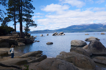 Fototapeta na wymiar Tourist wearing a jeacket in the fall looking at the view at Sand Harbor State Park in Lake Tahoe