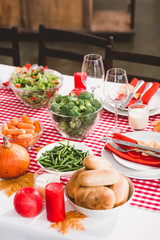 high angle view of table with salad, glasses, candles, vegetables, pies, plates and pumpkins in...