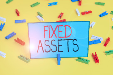 Text sign showing Fixed Assets. Business photo showcasing longterm tangible piece of property or equipment a firm owns Colored clothespin papers empty reminder yellow floor background office