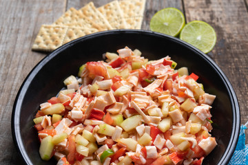 Surimi crab ceviche with cucumber and tomato on wooden background