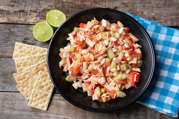 Surimi crab ceviche with cucumber and tomato on wooden background