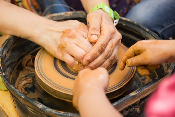 A close up view on ceramic production process on potter's wheel with children. Clay crafts with kids concept.