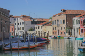 Murano Island, Venice. Buildings, canal, boats at the quays, general plan