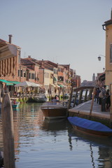 Murano island, Venice, canal, boats and street spree. Beautiful setting sun